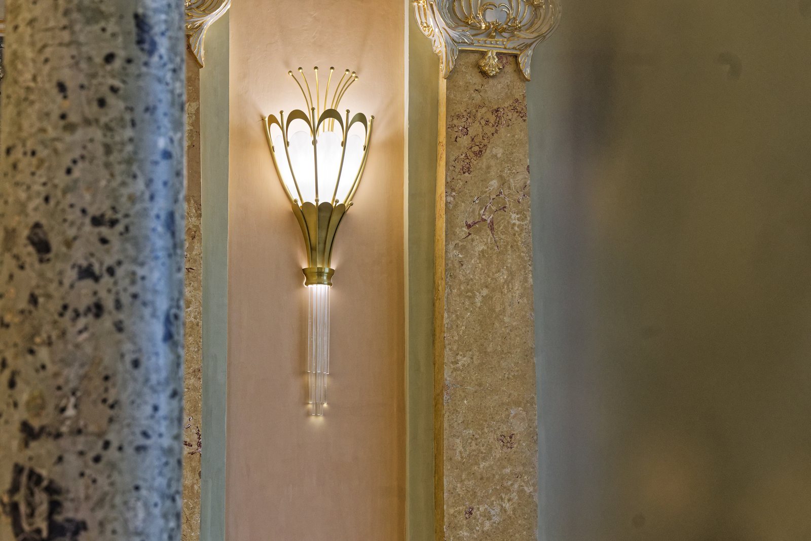 Aplică de perete Art Nouveau aprinsă, montată între două coloane de marmură