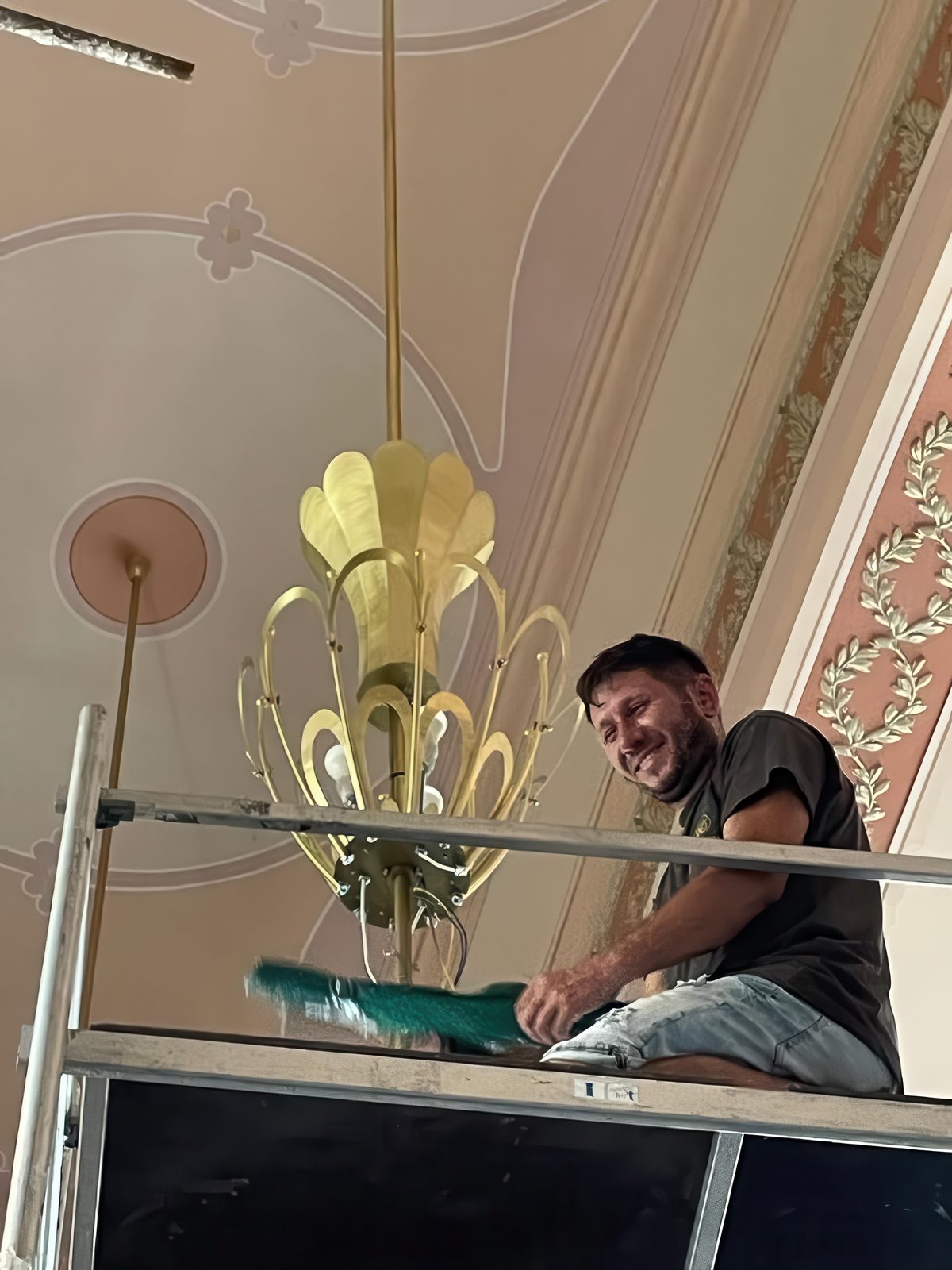 Meșter pe schelă lângă un candelabru, sub plafonul pictat al Cazinoului