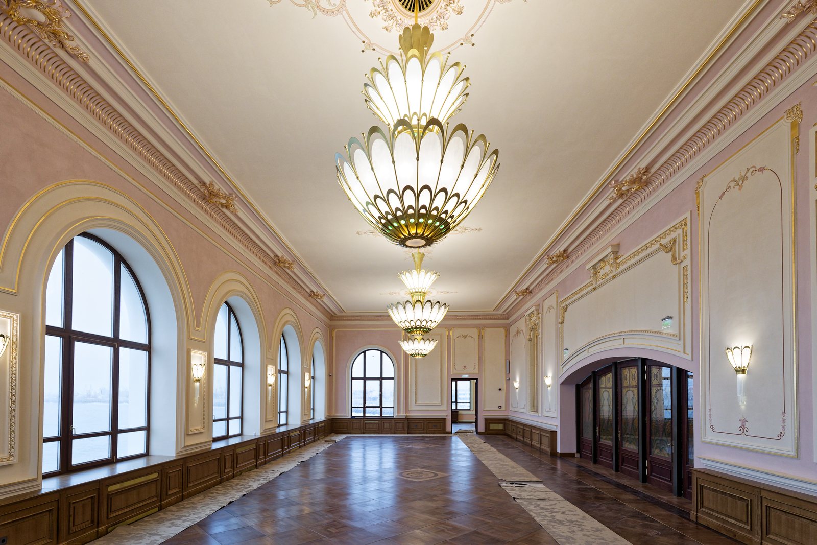 Salon lung cu ferestre arcuite și candelabre Art Nouveau cu petale de sticlă opal, aprinse