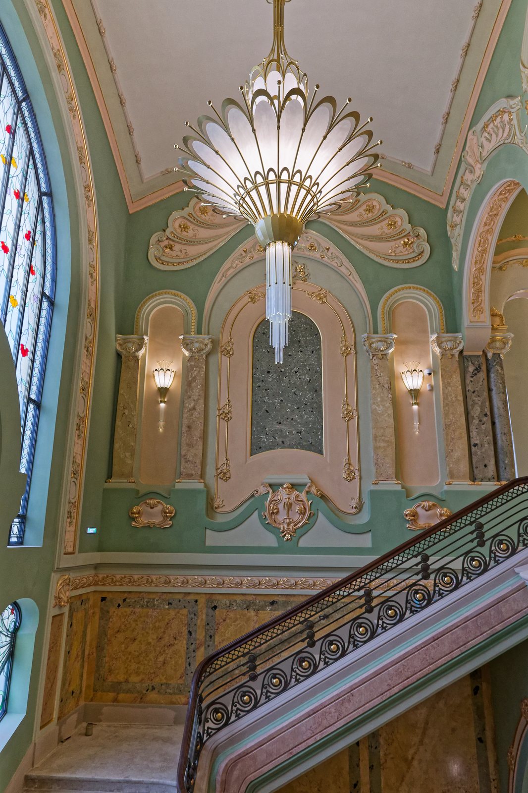 Candelabru Art Nouveau și aplice aprinse pe scara de onoare, cu balustrada din fier forjat în prim-plan