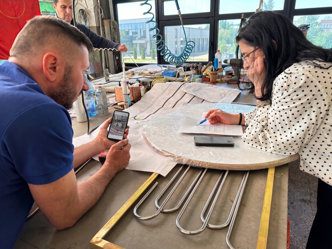 Designer și meșter analizând desene tehnice pe masa de lucru din atelier