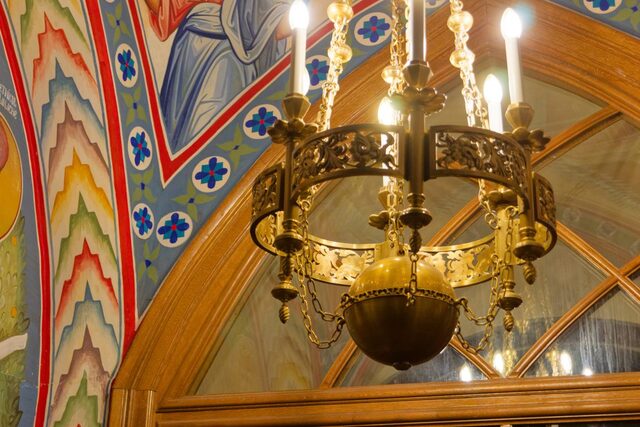 Detaliu al unui candelabru mic din alamă, cu sfera de la bază și inelul traforat