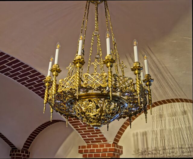 Candelabru din alamă cu 12 brațe, pe bolta albă cu nervuri de cărămidă a pronaosului
